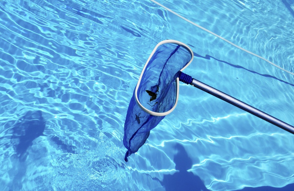 Professional pool cleaning with net removing leaves in Adelanto, CA