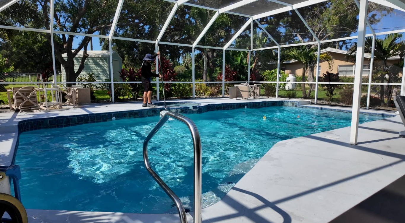 Professional pool technician cleaning screened pool enclosure in Adelanto, CA